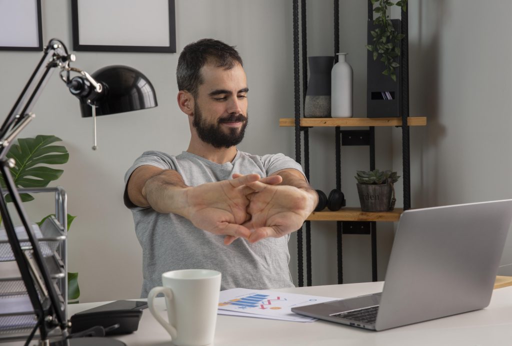 3 Exercícios laborais para quem trabalha sentado 4 man stretching his arms while working from home